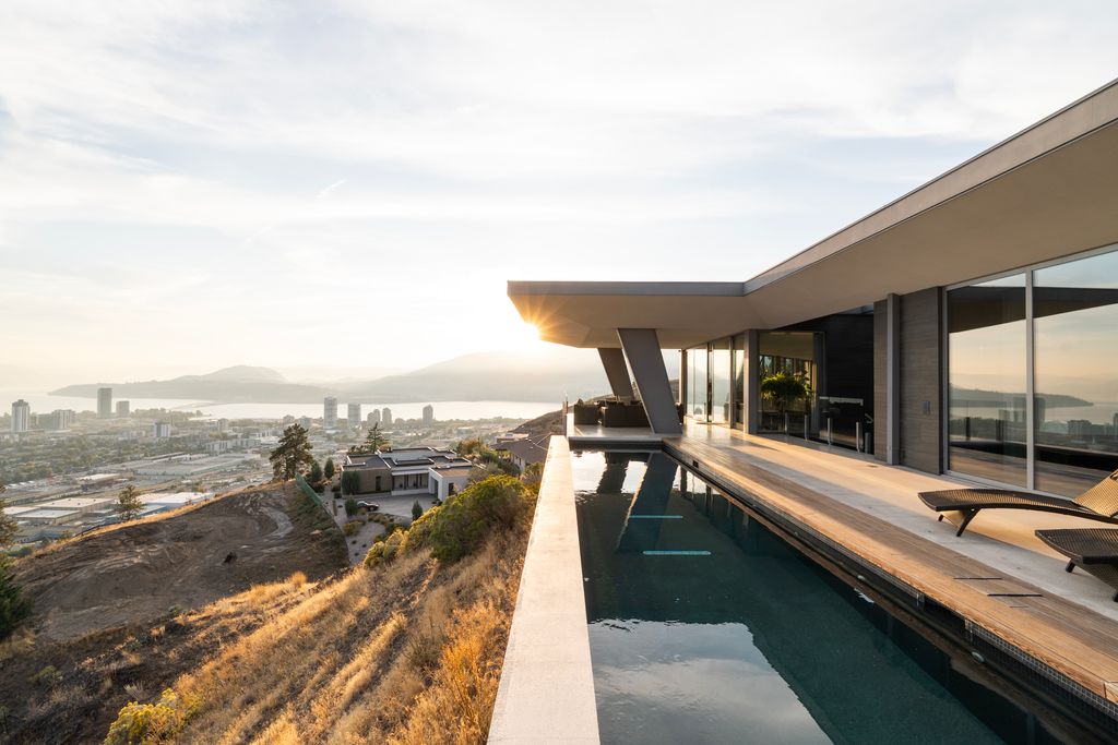 Modernist hillside residence with a cantilevered lap pool overlooking the city and water at sunset